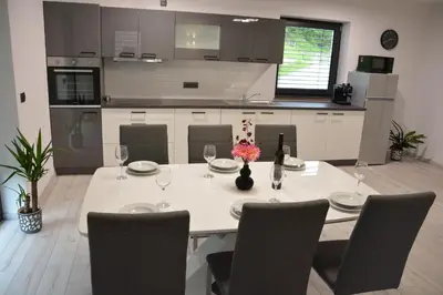a kitchen with a table and chairs with wine glasses at House Under The Maple Tree in Vitanje