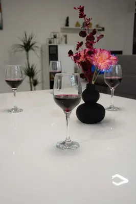 three wine glasses on a table with a vase of flowers at House Under The Maple Tree in Vitanje