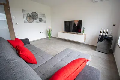 a living room with a gray couch and red pillows at Holiday house Oljka in Kobdilj