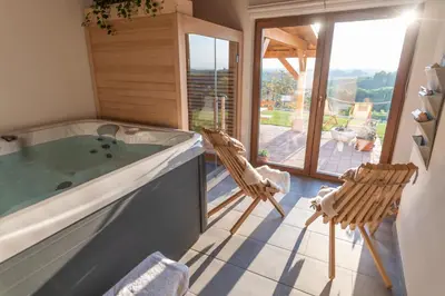 a bathroom with a tub and chairs and a balcony at Hill Cottage Haloze in Gruškovec