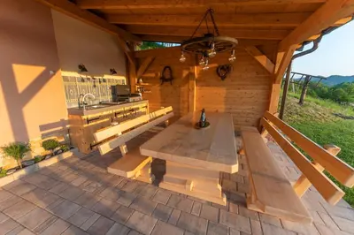 a wooden bench on a patio with a kitchen at Hill Cottage Haloze in Gruškovec