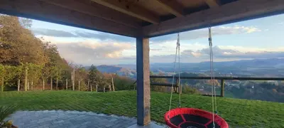a porch with a swing and a view of the mountains at Apartmaji Gračner in Dramlje