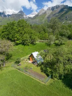 a small house in a field with mountains in the background at Tiny Eko House Bovec in Bovec