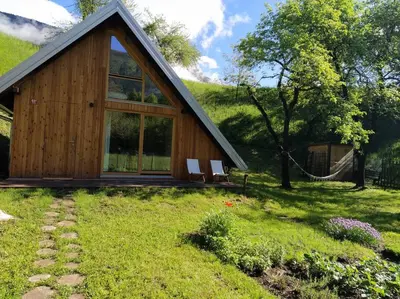 a wooden cabin with two chairs in the grass at Tiny Eko House Bovec in Bovec