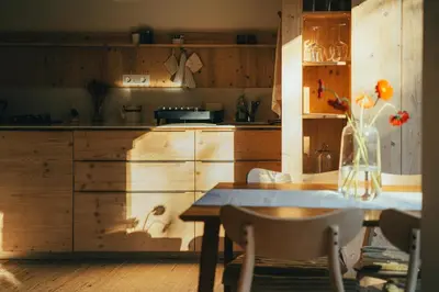 a kitchen with wooden cabinets and a table with a vase of flowers at Tiny Eko House Bovec in Bovec