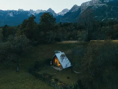a small cabin in a field with mountains in the background at Tiny Eko House Bovec in Bovec