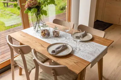a wooden table with plates and wine glasses on it at Tiny Eko House Bovec in Bovec