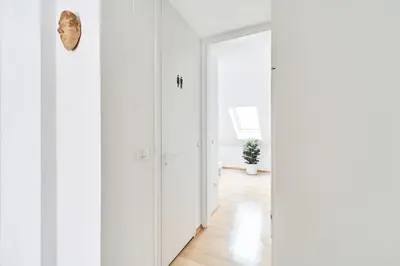 a hallway with white walls and a mirror at Matic Spacious Modern Apartment in Ljubljana
