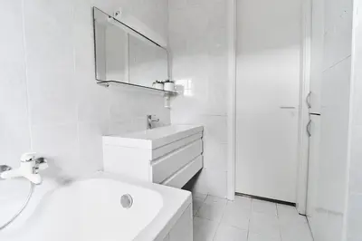 a white bathroom with a sink and a mirror at Matic Spacious Modern Apartment in Ljubljana