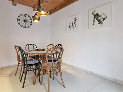 a dining room with a table and chairs and a clock at Smetova - The Blue Door House in Šempas