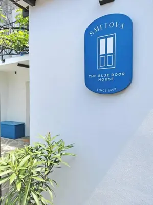 a blue sign on the side of a building with a plant at Smetova - The Blue Door House in Šempas