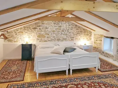 a bedroom with a white bed and a stone wall at Smetova - The Blue Door House in Šempas