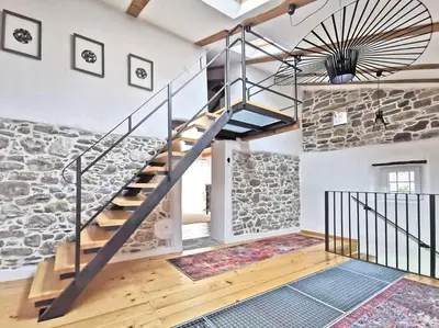 a staircase in a room with a stone wall at Smetova - The Blue Door House in Šempas