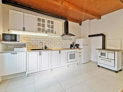 a kitchen with white cabinets and white appliances at Smetova - The Blue Door House in Šempas