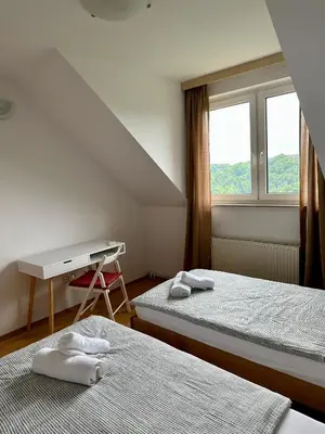 a room with two beds and a desk and a window at Karla’s House in Dobje pri Planini