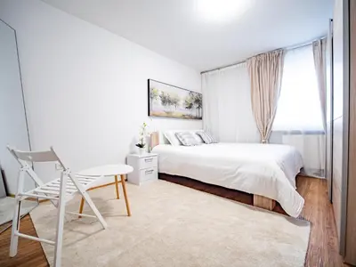 a white bedroom with a bed and a chair at Grand Family Residence Ljubljana in Ljubljana