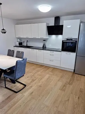 a kitchen with white cabinets and a table and a refrigerator at Grand Family Residence Ljubljana in Ljubljana