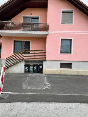 a pink building with a parking lot in front of it at Apartma Ivana in Markovci