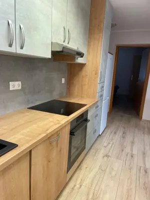 a kitchen with wooden cabinets and a wooden floor at Apartma Ivana in Markovci