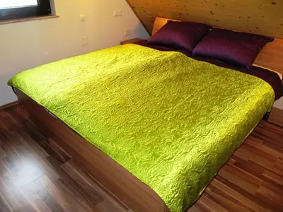 a green bed in a room with a wooden floor at Holiday Home Češnovar in Raka