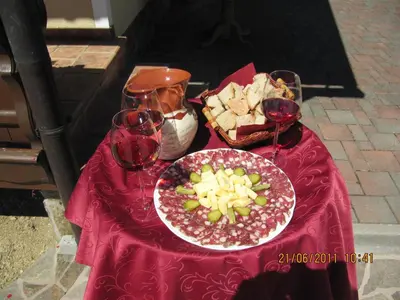 a red table with a plate of food and wine glasses at Holiday Home Češnovar in Raka