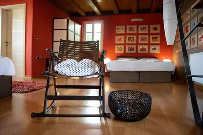 a rocking chair in a room with a bed at Klinec Plešivo Art Rooms in Dobrovo