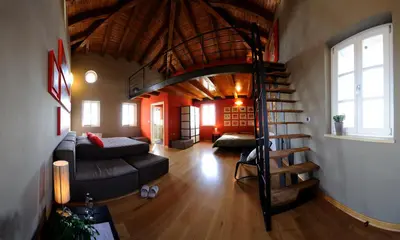 a living room with a couch and a spiral staircase at Klinec Plešivo Art Rooms in Dobrovo