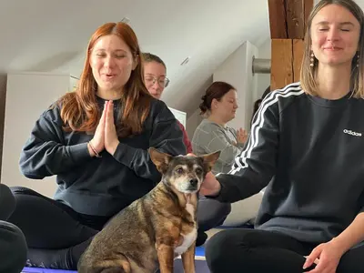 two women sitting on the floor with a dog at OM Yoga center in Slovenska Bistrica