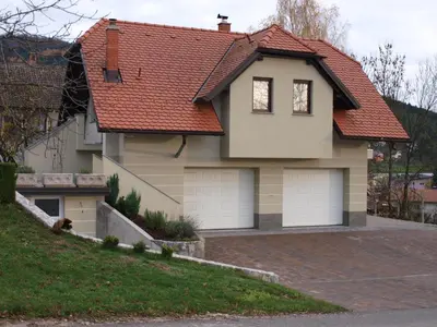 a house with two garage doors on a driveway at Apartment Knap in Cerknica