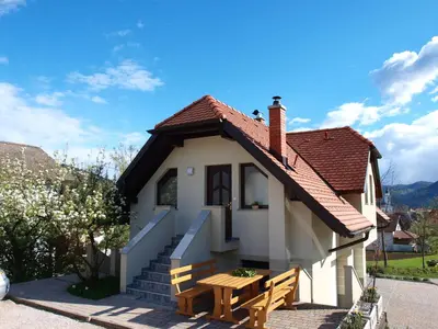 a small white house with a wooden table and a bench at Apartment Knap in Cerknica