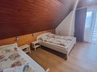 a bedroom with two beds and a wooden ceiling at Bed & Breakfast Hisa Resje in Bohinj