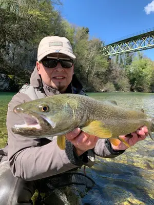 a man holding a large fish in a river at Guesthouse Pri Štefanu in Most na Soči