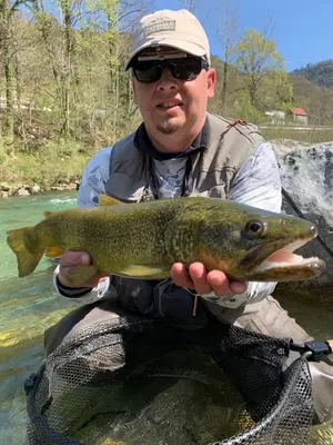 a man holding a brown trout in a river at Guesthouse Pri Štefanu in Most na Soči
