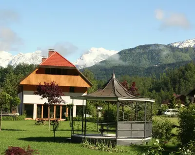 a gazebo in front of a house with mountains at Penzion Repnik in Kamnik