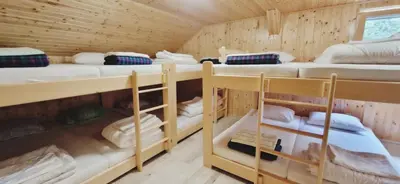 a room with four bunk beds in a wooden cabin at Mountain hut Dom pod Storžičem in Tržič