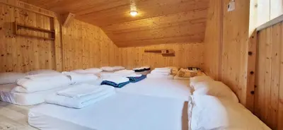 a room with white pillows in a wooden room at Mountain hut Dom pod Storžičem in Tržič