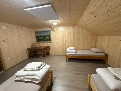 a room with two beds and a table in it at Mountain hut Dom pod Storžičem in Tržič