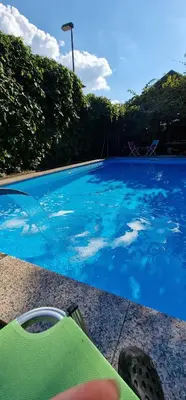 a blue swimming pool with a person sitting next to it at APARTMAN MURKO P-4 in Ljubljana