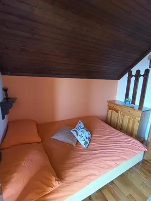 a bed in a room with a wooden ceiling at Kralj Matjaž - the green escape under Alps in Golnik