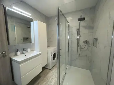 a bathroom with a shower and a washing machine at APARTMA DŽANA in Žaga