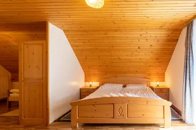 a bed in a room with a wooden ceiling at Apartment Malej in Bohinj