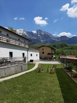a building with two picnic tables and mountains in the background at Holiday House Dori in Kobarid