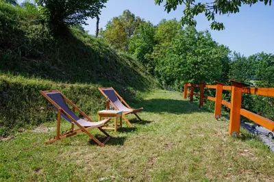 three chairs sitting in the grass next to a fence at Bomas house in Cerkno