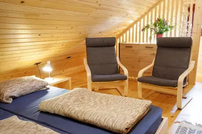 two chairs and a bed in a room with wooden walls at Bomas house in Cerkno