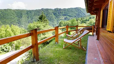a porch of a house with a rocking chair on it at Bomas house in Cerkno