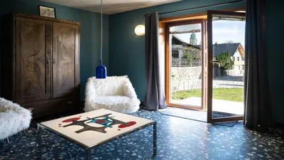 a living room with a table and a chair and a door at Vila Vrba in Žirovnica