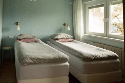 two beds in a room with a window at Quiet apartment with a terrace on Organic farm in Prevalje