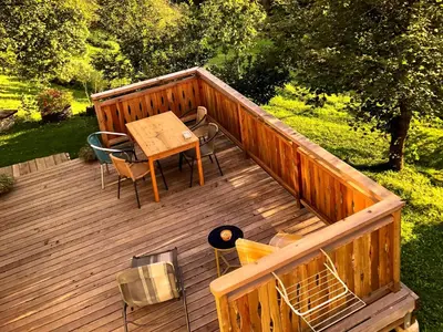 a wooden deck with a table and chairs on it at Quiet apartment with a terrace on Organic farm in Prevalje