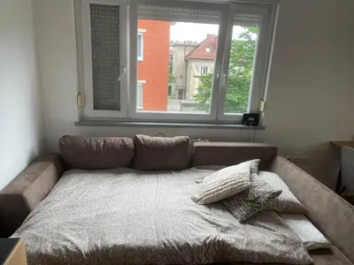 a couch in a living room with a window at Mely Rose in Ljubljana