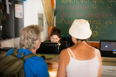 two women standing at a counter looking at a woman at Hostel Soča Rocks in Bovec